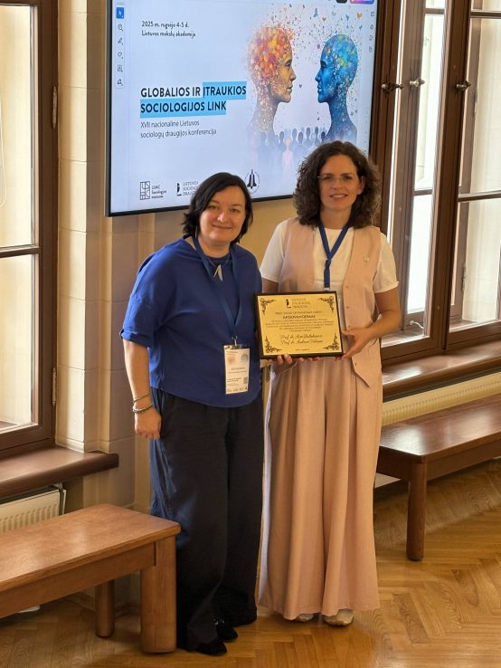Dvi moterys laiko apdovanojimo diplomą