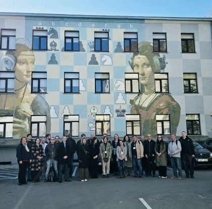 Žmonių grupė pozuoja prie sienos sustoję į eilę