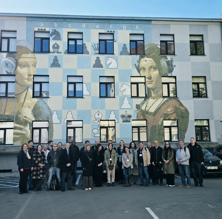 Žmonių grupė pozuoja prie sienos sustoję į eilę